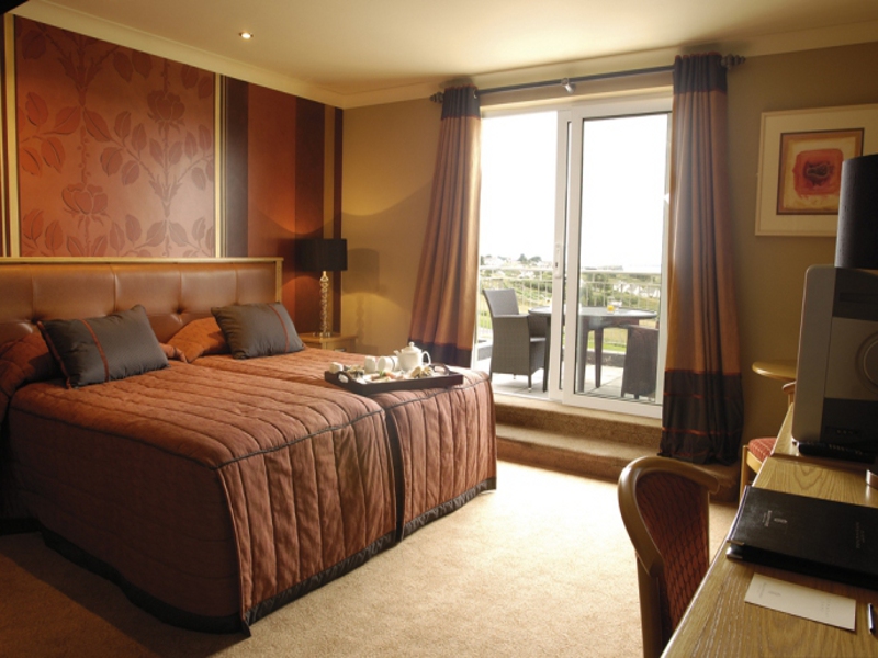 Twin bedroom with red décor at Ballyliffin Lodge and Spa Hotel and patio balcony with views of the golf course