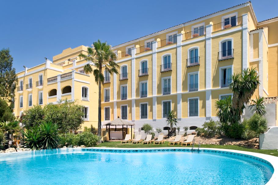 Swimming pool with sun loungers overlooked by rooms in the hotel at Barcelo Montecastillo Golf Resort