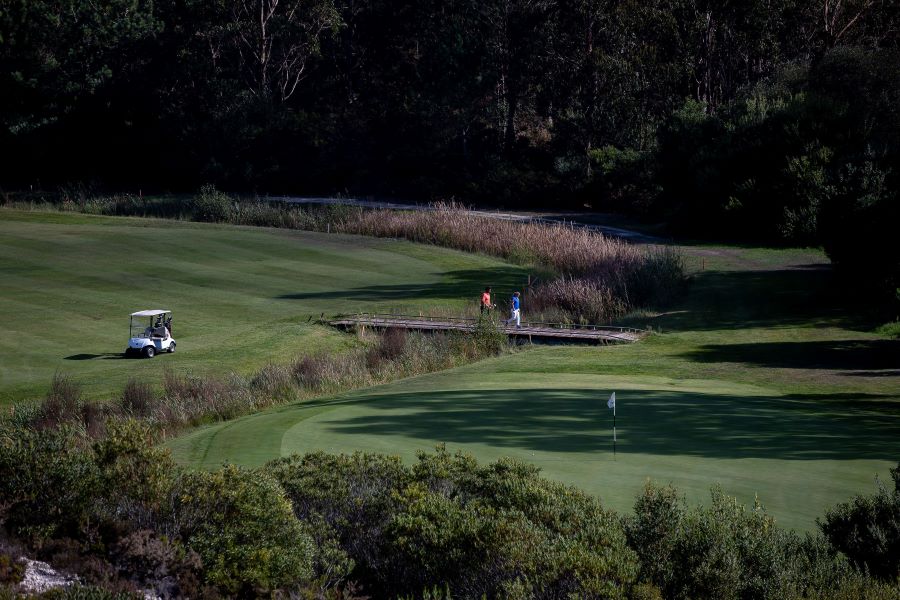 Golfers walking over a bridge to the green at Lisbon's Bom Sucesso golf course