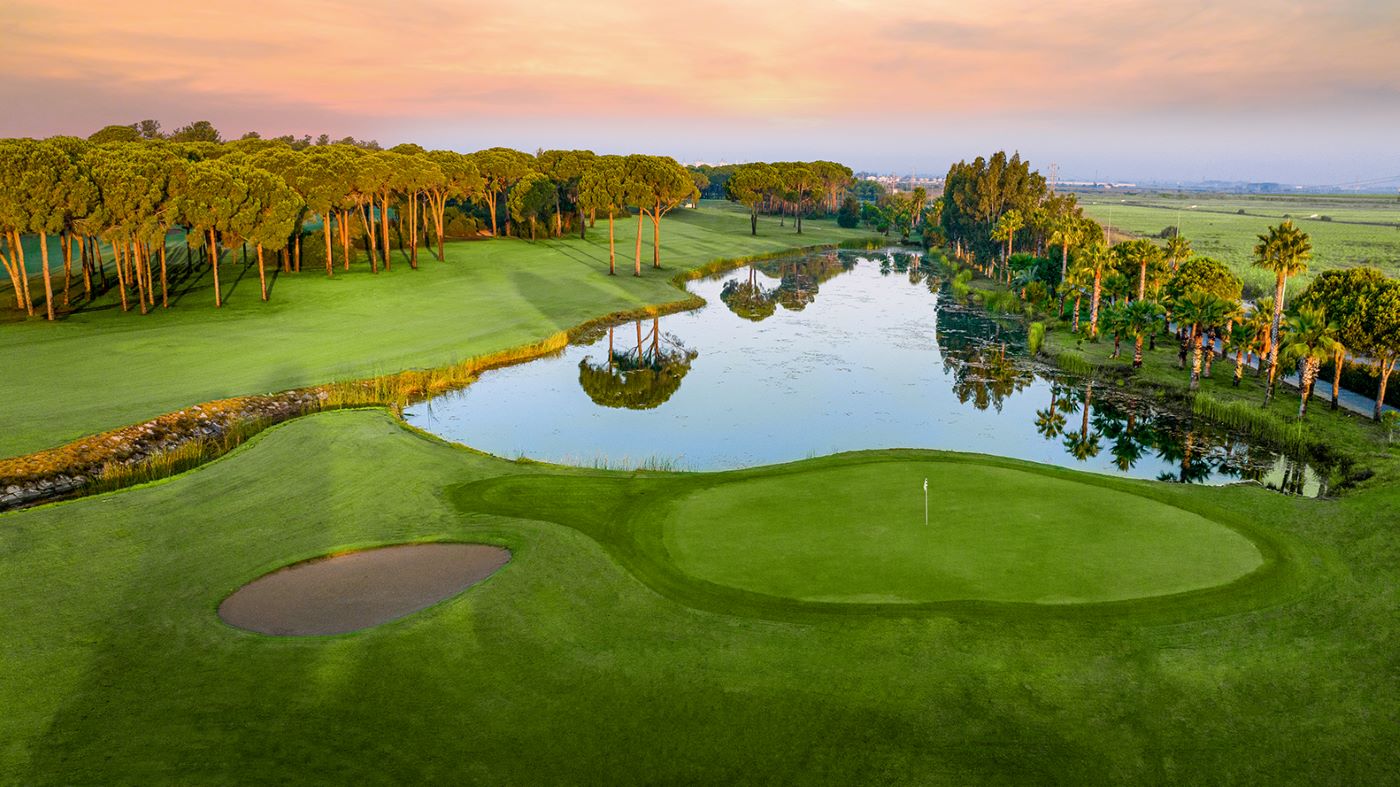 Lake at Gloria Golf Club with sun setting in background