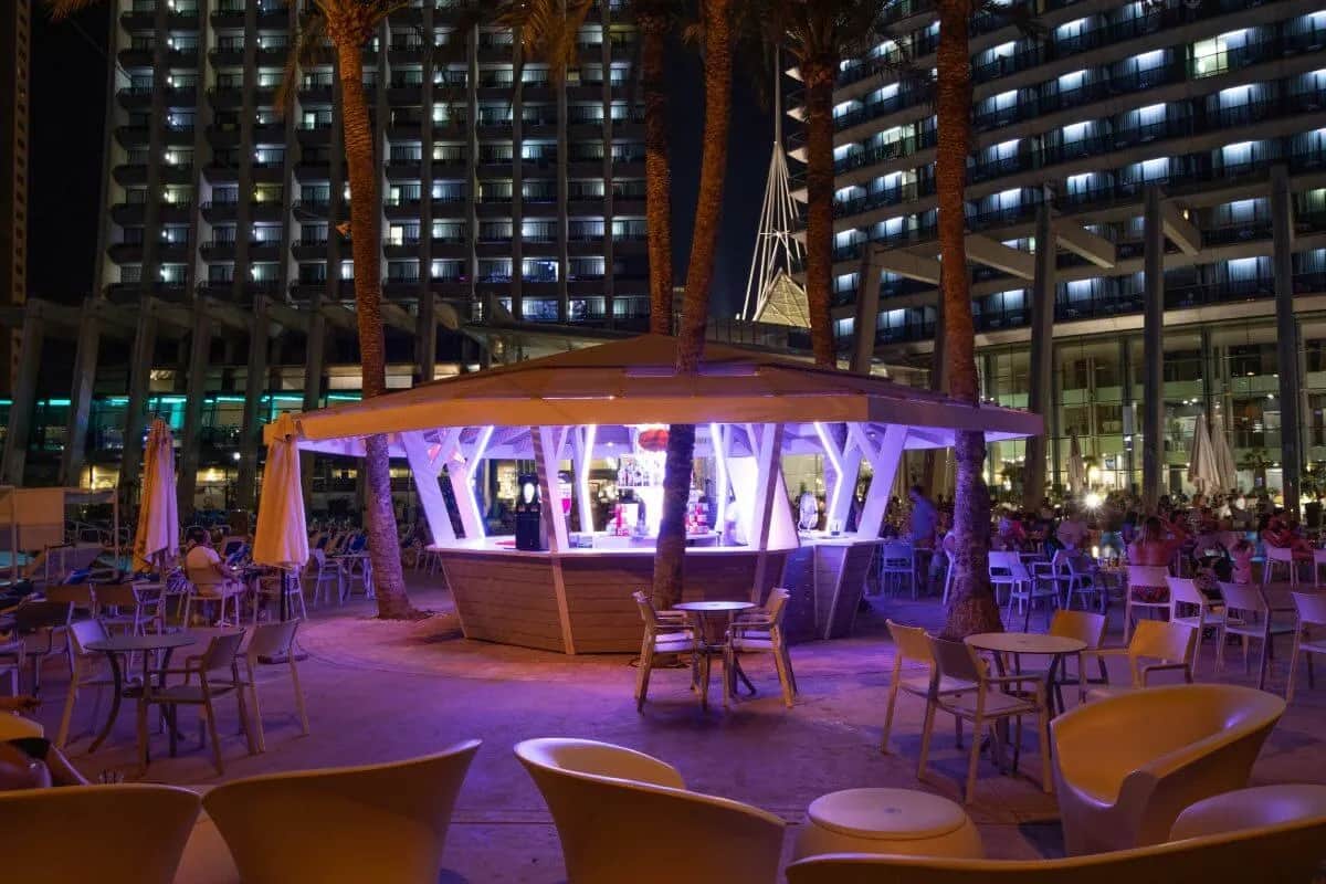 Beach bar with tables and chairs, lit up by purple light at Gran Hotel Bali