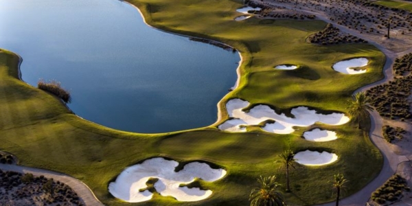 Hacienda Riquelme golf course with green fairway wrapping around blue lake