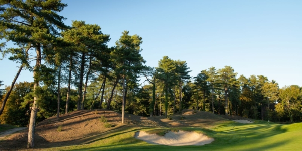 Trees on the edge of fairway, overlooking a bunker, on the first hole at Hardelot Les Pins course in France