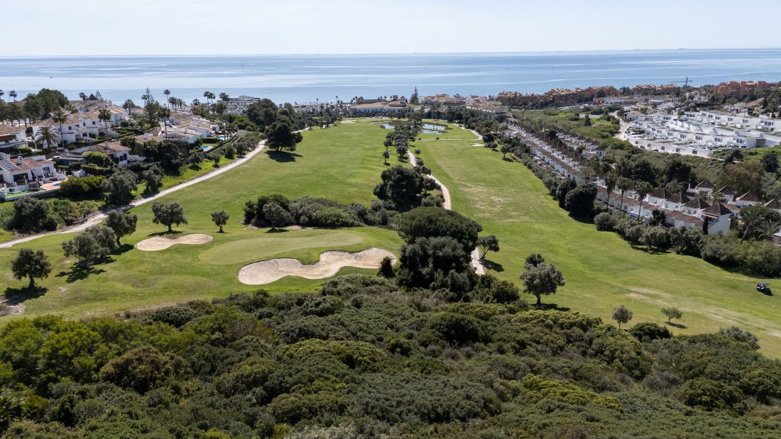 Bunker and numerous fairways visible with sea and apartments surrounding La Duquesa Golf Club