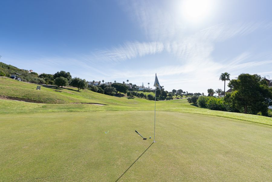Flag on the green with sun overhead at La Duquesa Golf Club in the Costa Del Sol