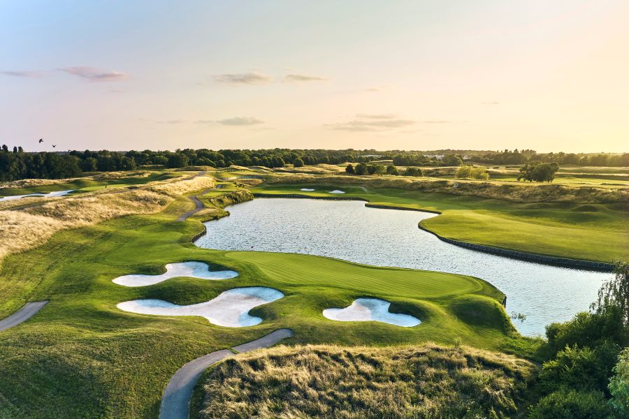 Three bunkers to one side of putting green, and lake to the other at Le Golf National