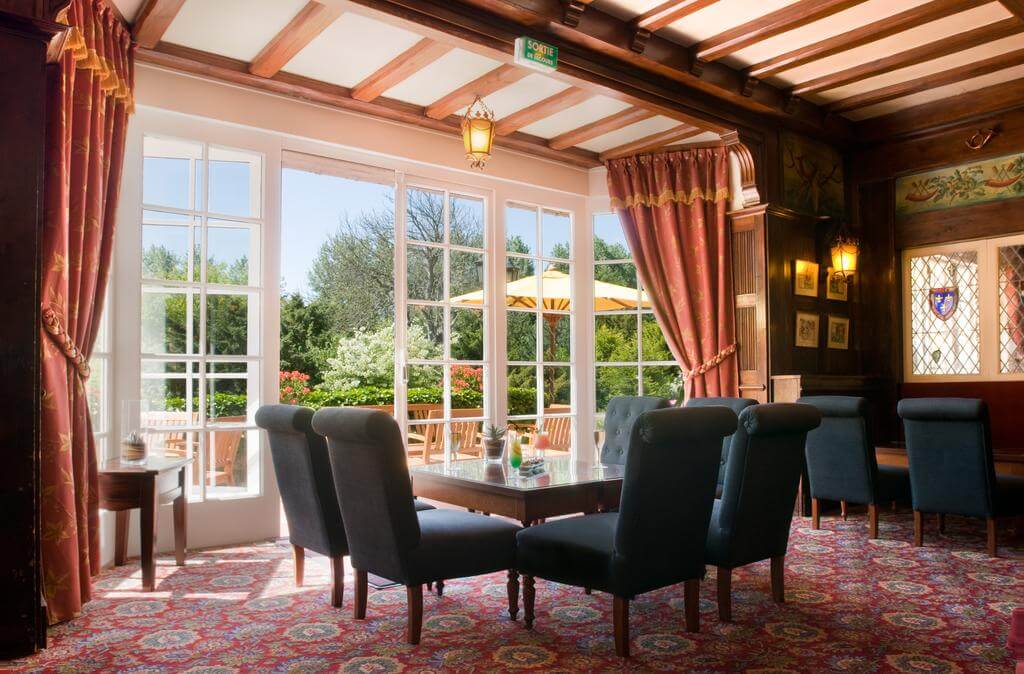 Seating area at Le Manoir Hotel with patio doors leading to gardens