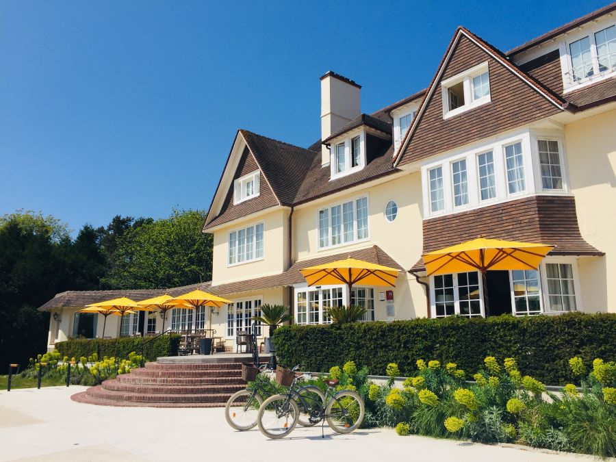 Exterior of Le Manoir Hotel Le Touquet with yellow parasols and bicycles outside the hotel