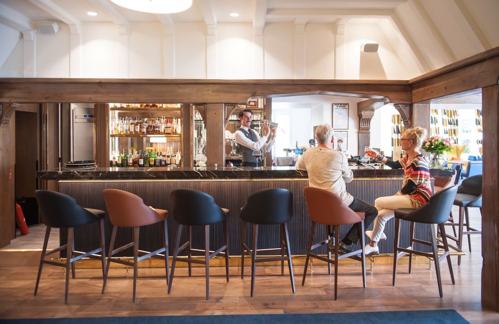 Bar with guests enjoying drinks at Le Manoir Hotel