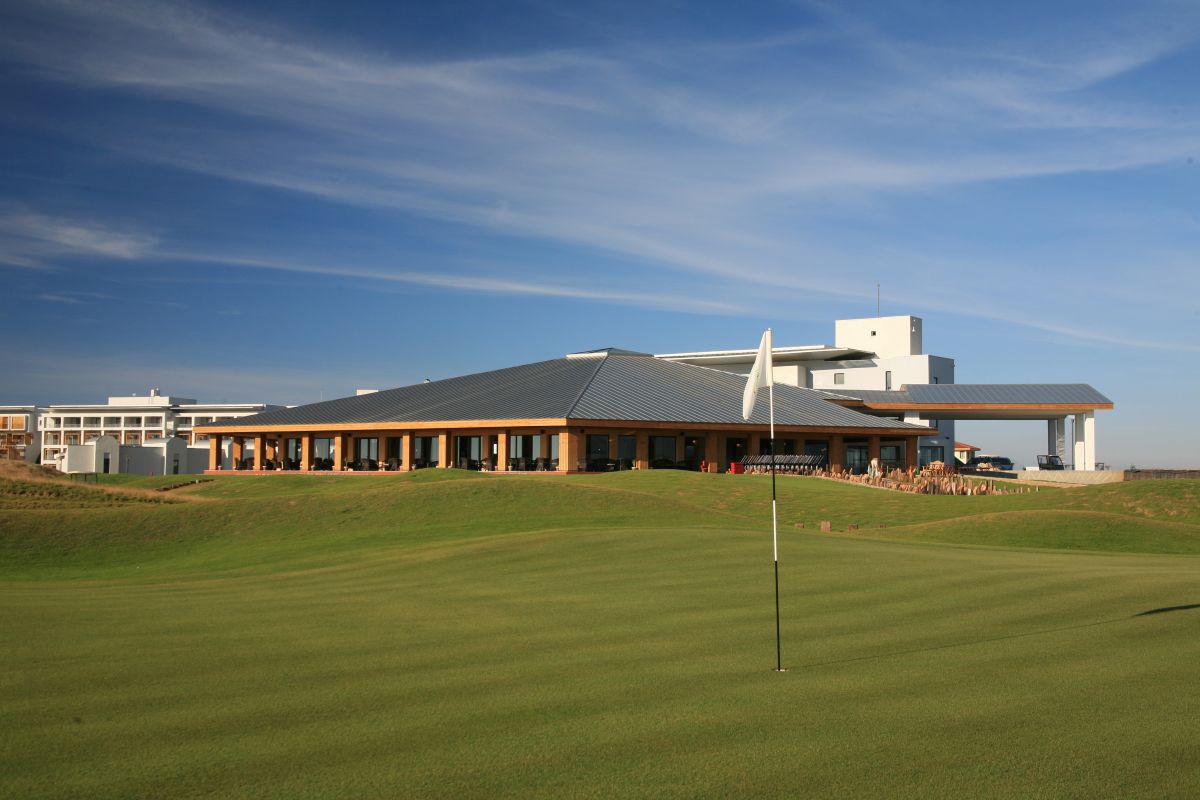 Flag on the green with clubhouse in the distance at Lykia Links