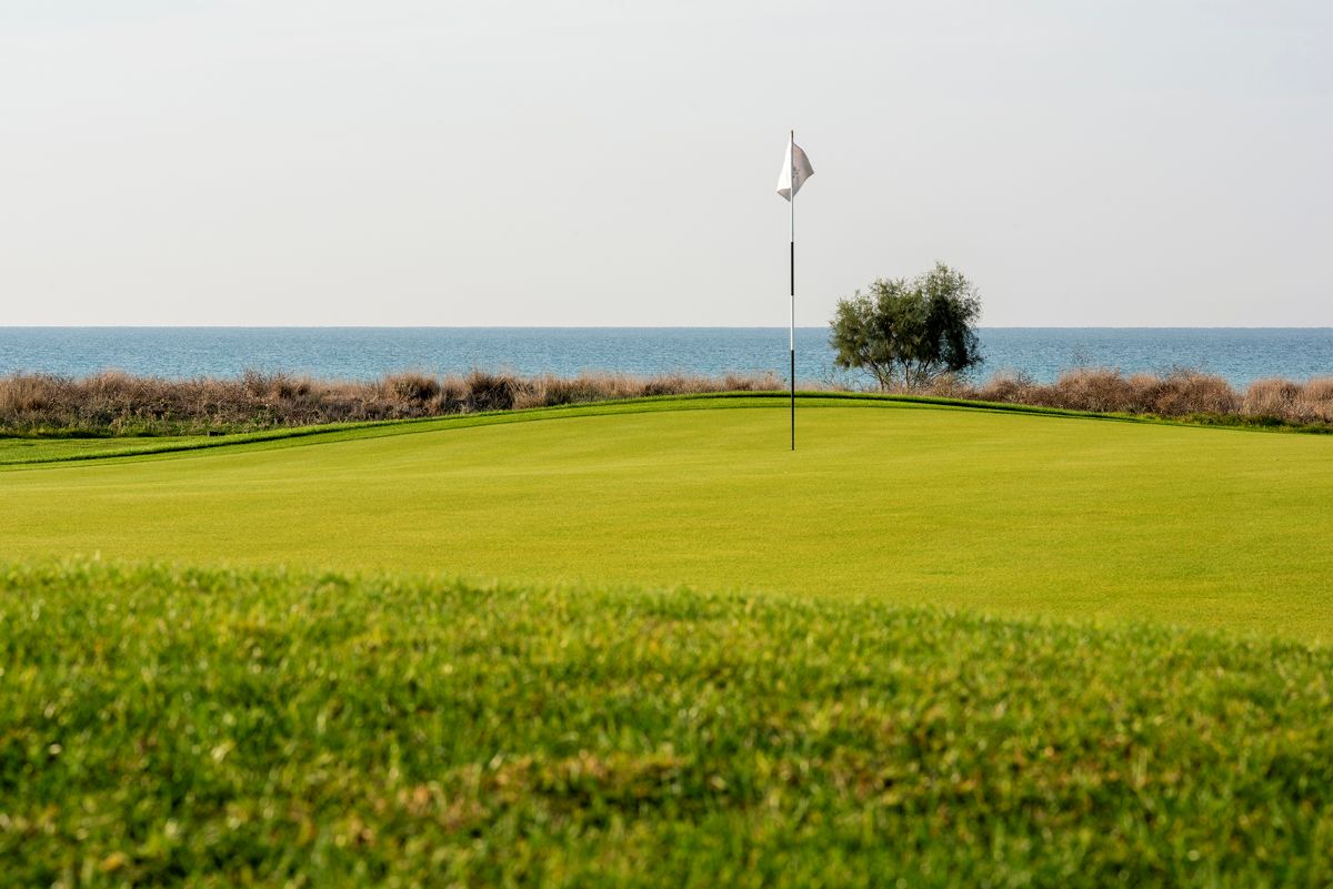 Flag on the putting green overlooking the sea at Lykia Links Golf Club