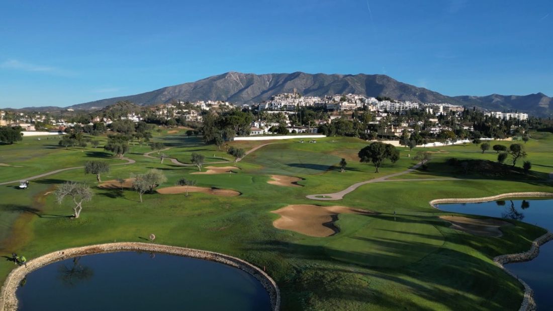 Mountain in the distance with whitewash houses dotted along it, with Mijas Golf Course in the foreground