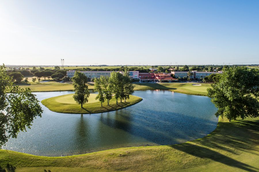 Large lake with island and green trees in front of hotel at Montado Golf Course