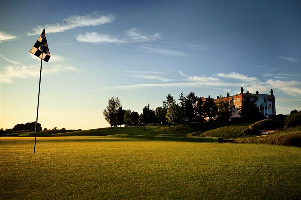 Novotel Saint Quentin Golf National protected by trees overlooking the golf course with flag in the hole