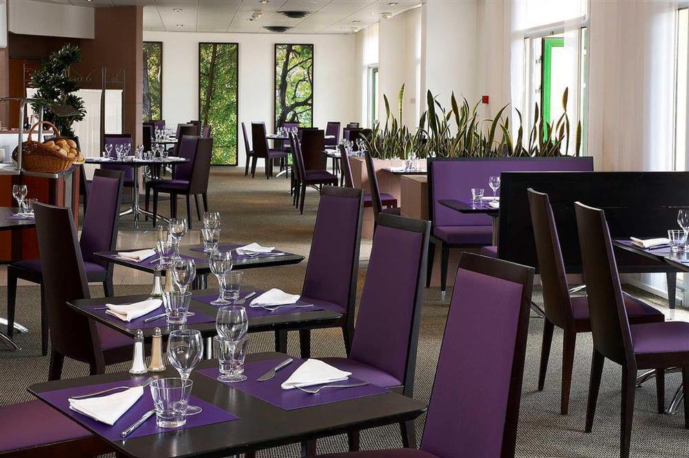 Novotel Saint Quentin Golf National dining room with tables set and purple chairs