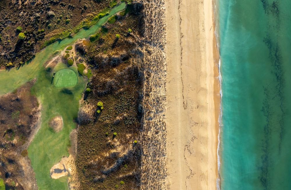 Turqiouse water of the sea lapping against the sand with the golf course next to it at Palmares Golf