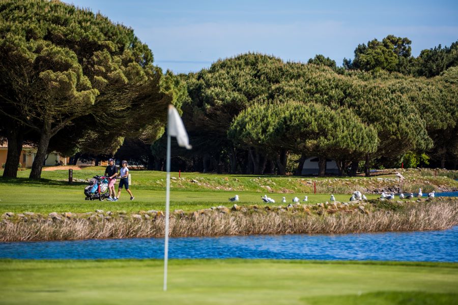 White flag on green with golfers in distance at Quinta Da Marinha golf course in Portugal's Silver Coast region