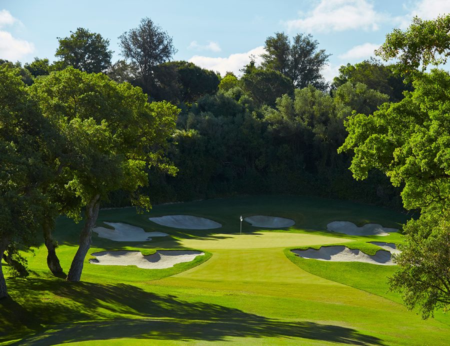 Hole 6 with six bunkers protecting the green, surrounded by trees at Real Club Valderrama