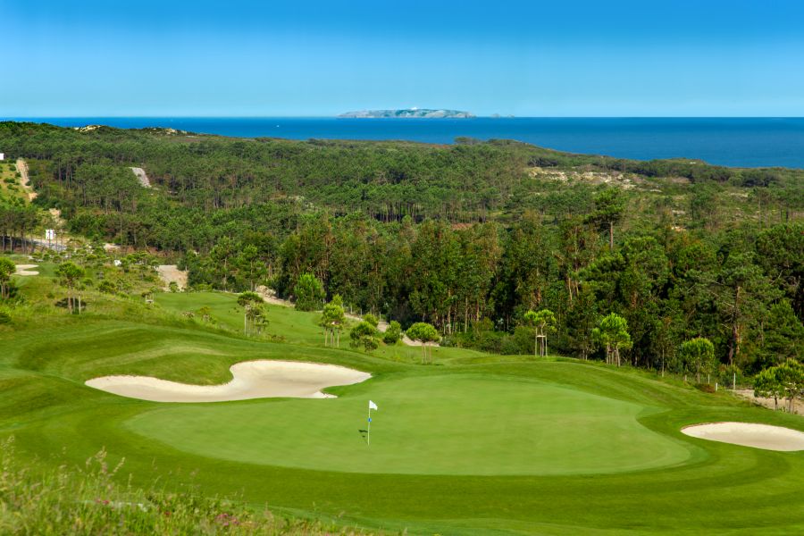 Putting green with flag, with trees in the distance at Royal Obidos