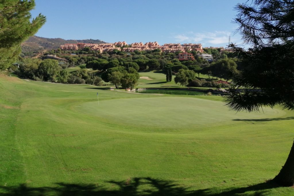 Large putting green with villas and apartments in the distance at Santa Maria Golf And Country Club in Costa Del Sol
