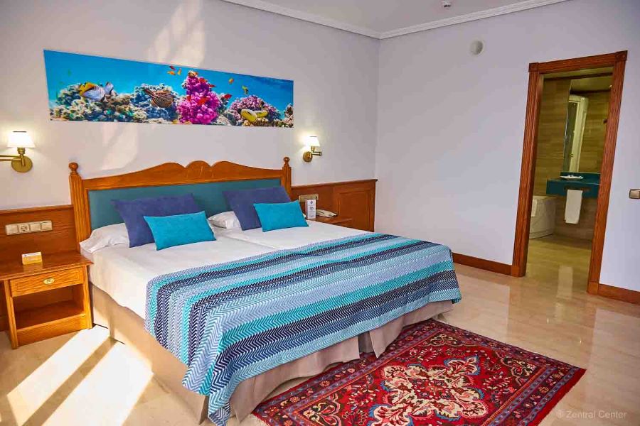 Bedroom in Zentral Center Hotel, with blue throw on bed and pine furniture