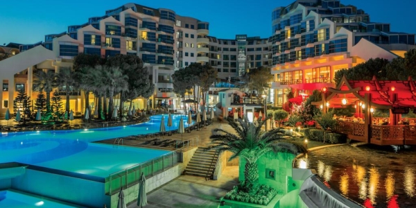 Cornelia Deluxe Resort in Belek at night with lights illuminating the outdoor swimming pool and bar