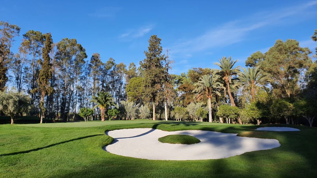 Large bunker, blue sky and green trees at Royal Golf Marrakech