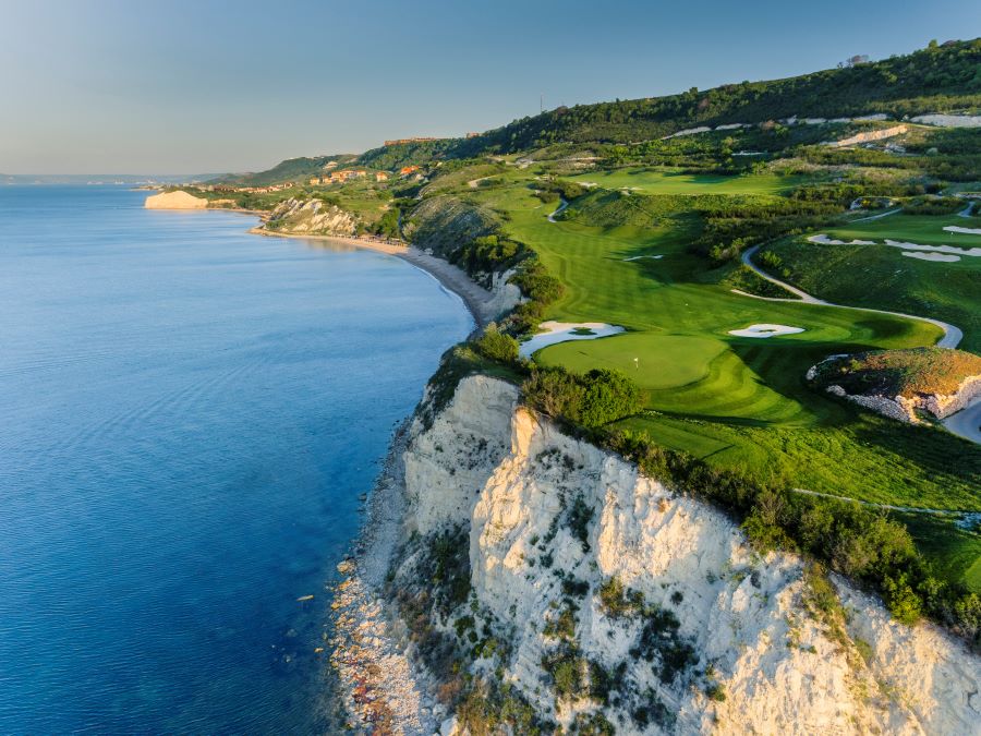 White cliff face with Thracian Cliffs golf course above it and sea to the left