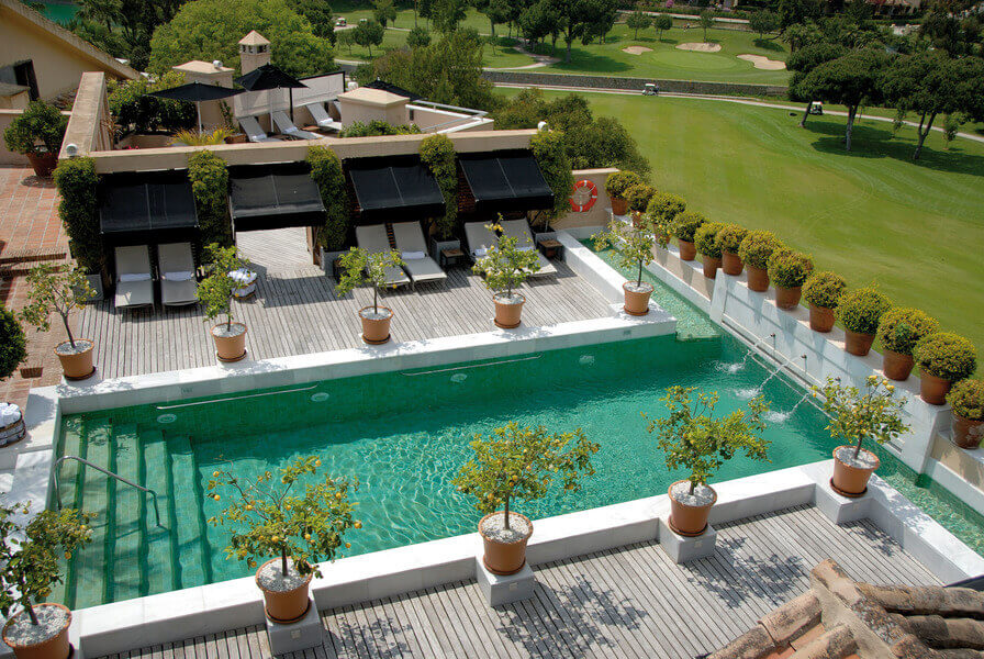 Swimming pool on the roof at Rio Real Golf Hotel with sun loungers and trees surrounding it