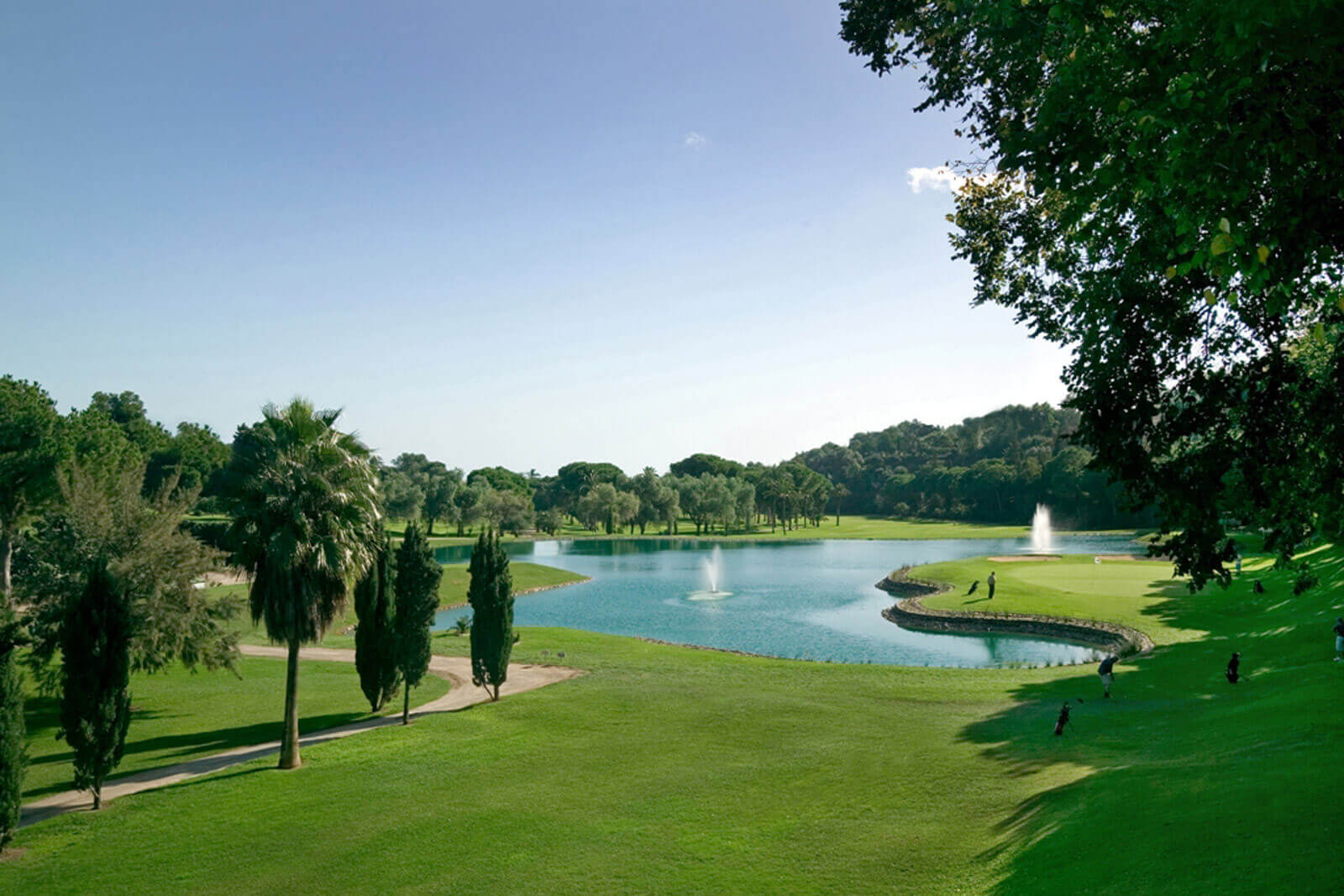 Golf course at Rio Real Golf Hotel with two fountains in the centre of the lake and four golfers playing towards the green