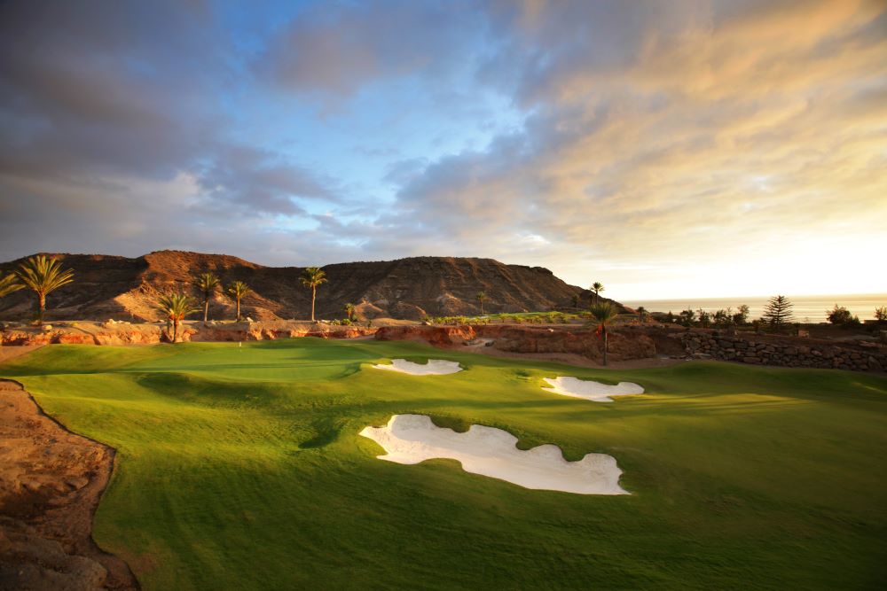 Sunset at Anfi Tauro Golf Club with large rock in the distance and bunkers in the foreground