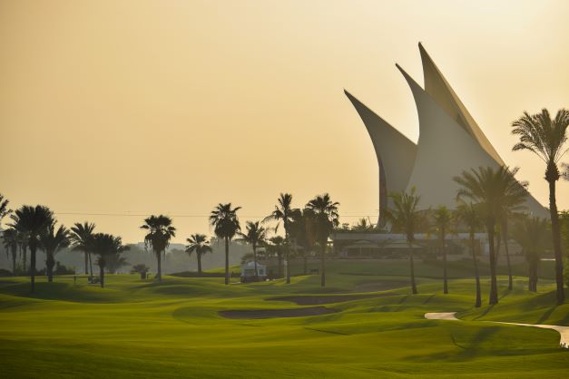 Dubai Creek Golf Club with club house in distance at sunset