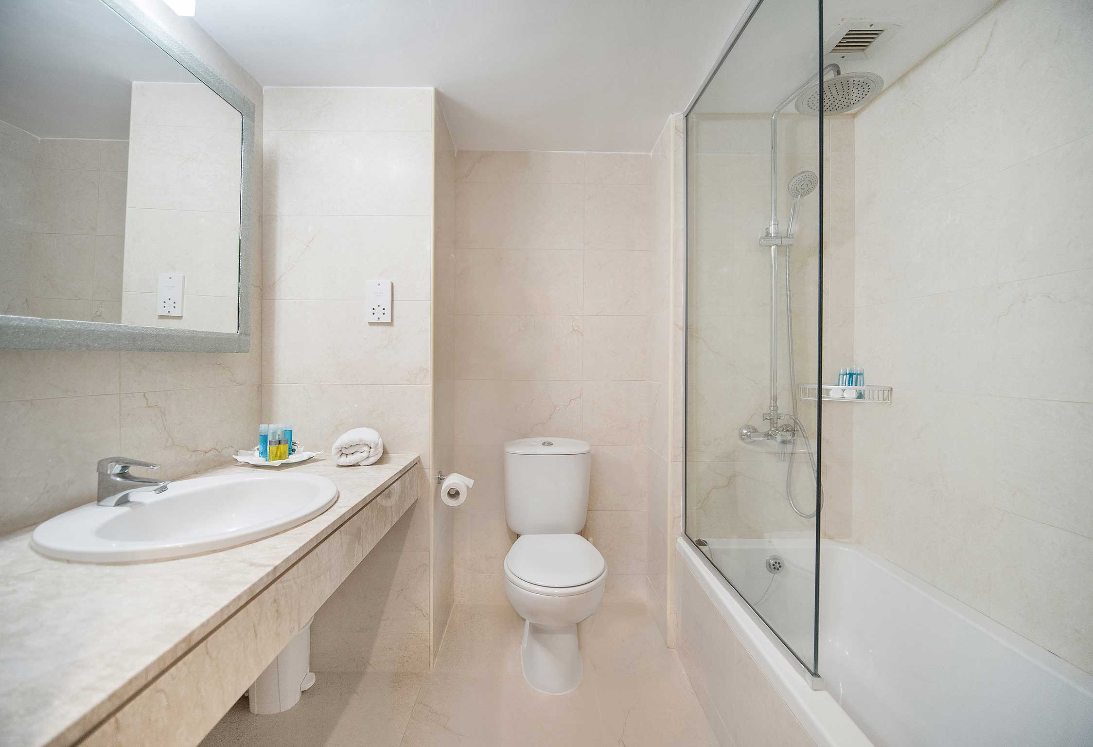 Bathroom at Avilda Hotel in Paphos with sink, mirror, toilet, bath tub and shower