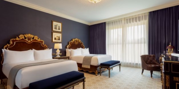 Twin beds in Standard room, blue wall and curtains covering window with views of the golf course