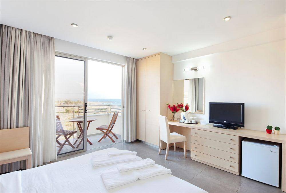 Double bedroom at Capital Coast Resort And Spa with private balcony, television, desk and minibar