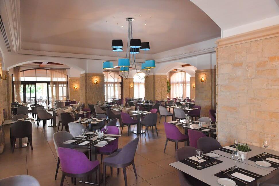 Restaurant at Aphrodite Hills Resort with tables set and purple chairs