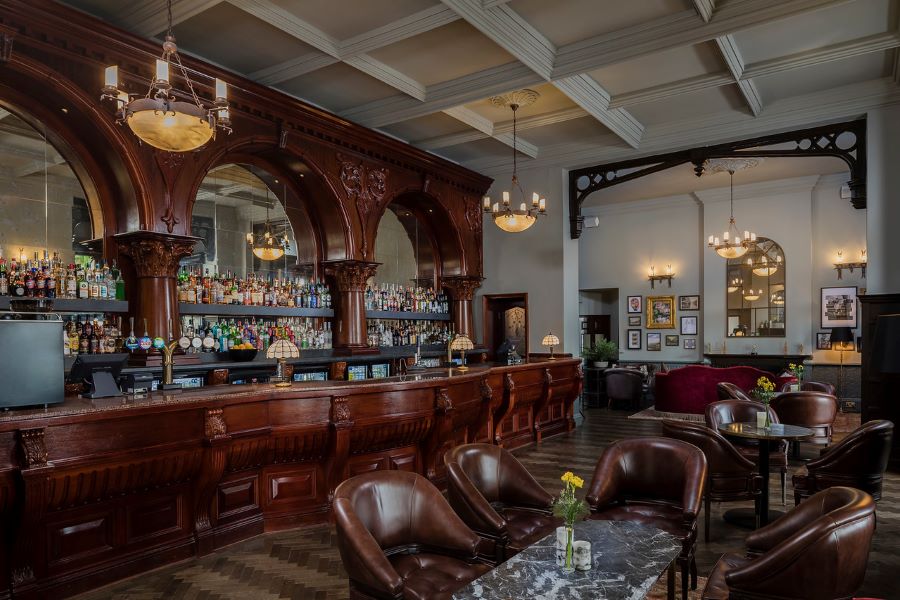 Bar with leather chairs and wooden panels at Dunston Hall Golf And Spa