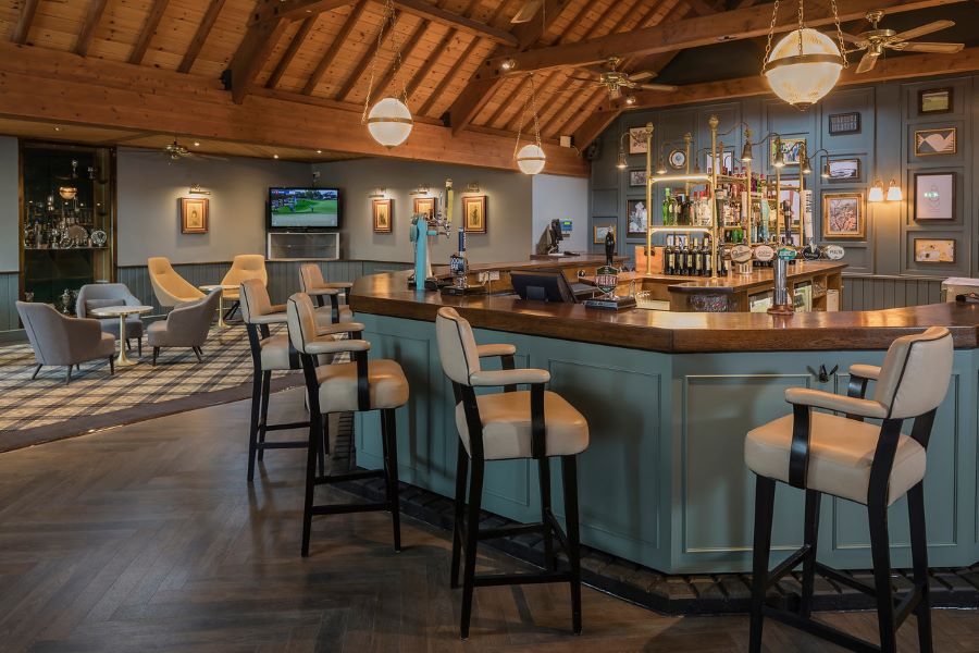Bar with stools and green wood panels at Dunston Hall Golf And Spa