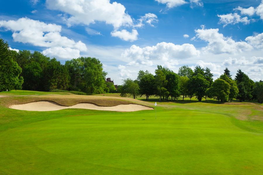 Long sand bunker protecting the green with lush green grass and cloudy blue sky at Dunston Hall Golf And Spa