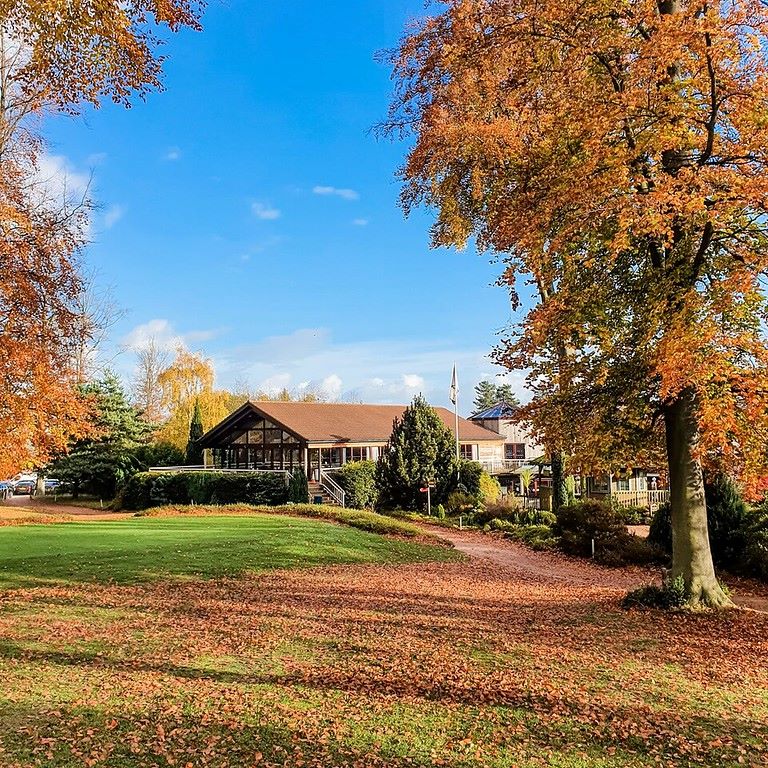 Trees overhanging the right of the golf course with the clubhouse in the distance at Forest Pines Hotel, Spa And Golf Resort