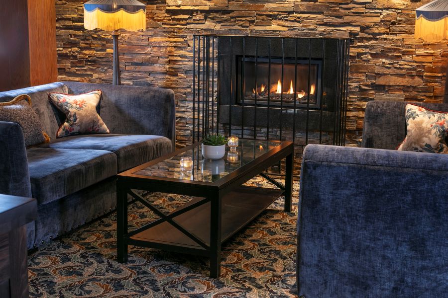 Blue sofas and table by open fire at Glasgow Westerwood Hotel, Spa & Golf Resort