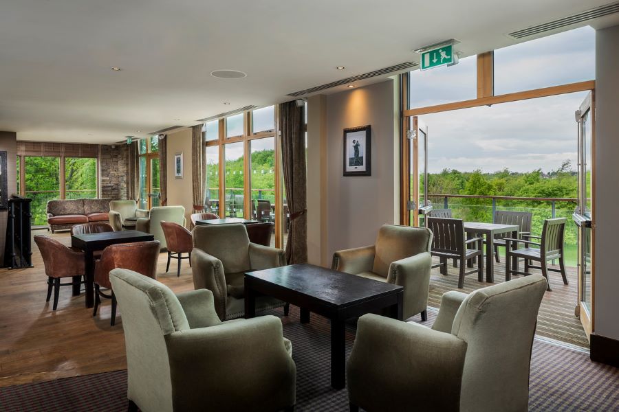Green chairs in the lounge area with views across the grounds at Oulton Hall Golf Hotel And Spa