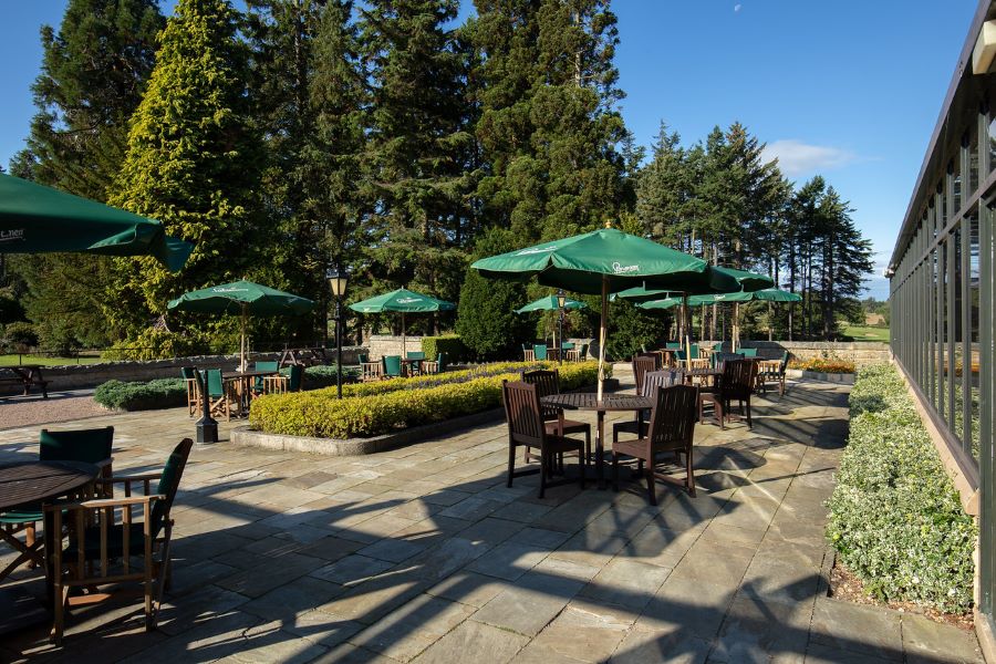 Outdoor seating area with wooden tables and chairs at Slaley Hall Hotel, Spa And Golf Resort