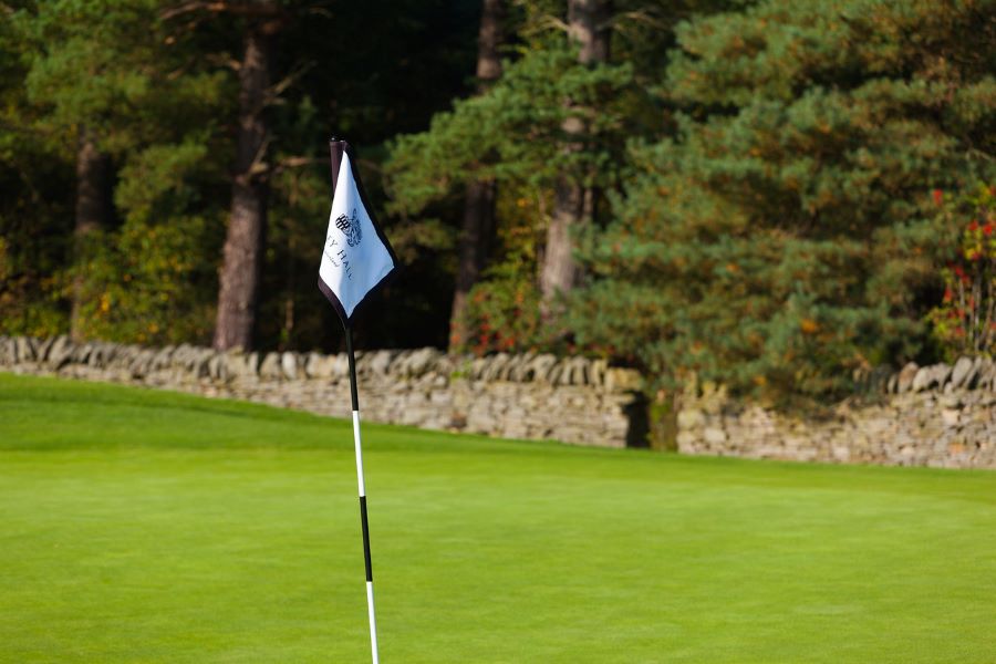 White flag on the putting green and stone wall in the distance at Slaley Hall Hotel, Spa And Golf Resort