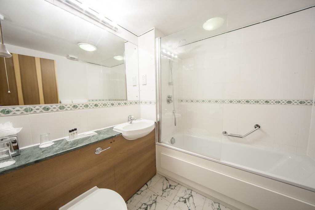 Bathroom with shower, toilet, sink and mirror at Hellidon Lakes Golf & Spa