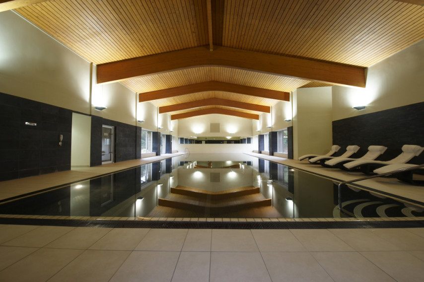 Indoor swimming pool with sun loungers at Heythrop Park Golf Resort