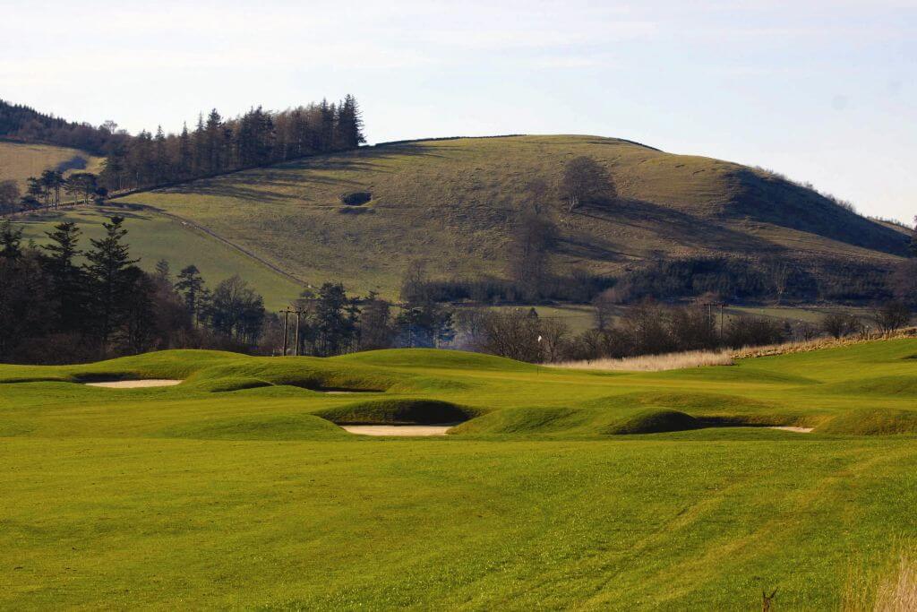 Green of the golf course with a large hill in the background at Macdonald Cardrona Hotel Golf And Spa