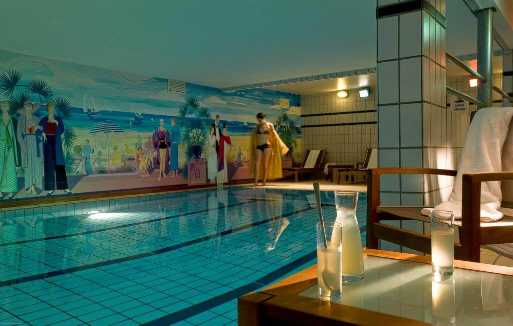 Guest stepping into indoor swimming pool at Hotel Barriere Le Westminster