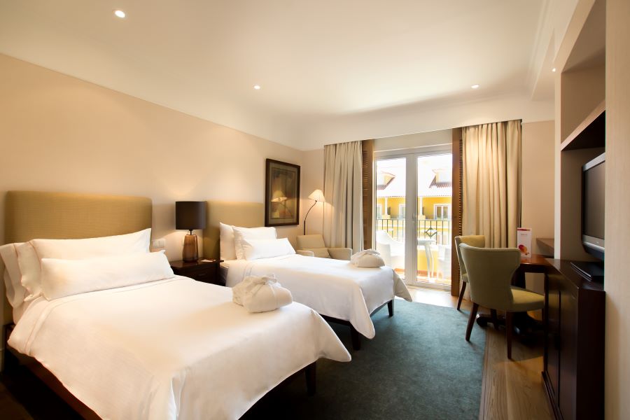 Twin beds in room with green carpet at Dolce by Wyndham CampoReal Lisboa