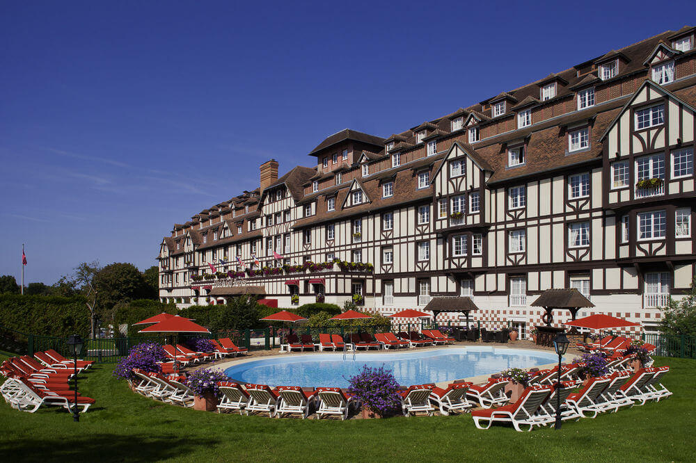 Rear of Hotel Barriere L'Hotel du Golf Deauville overlooking the outdoor swimming pool and sun lougers